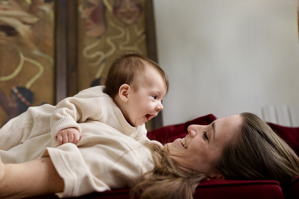 Mother and baby laughing together on a velvet couch