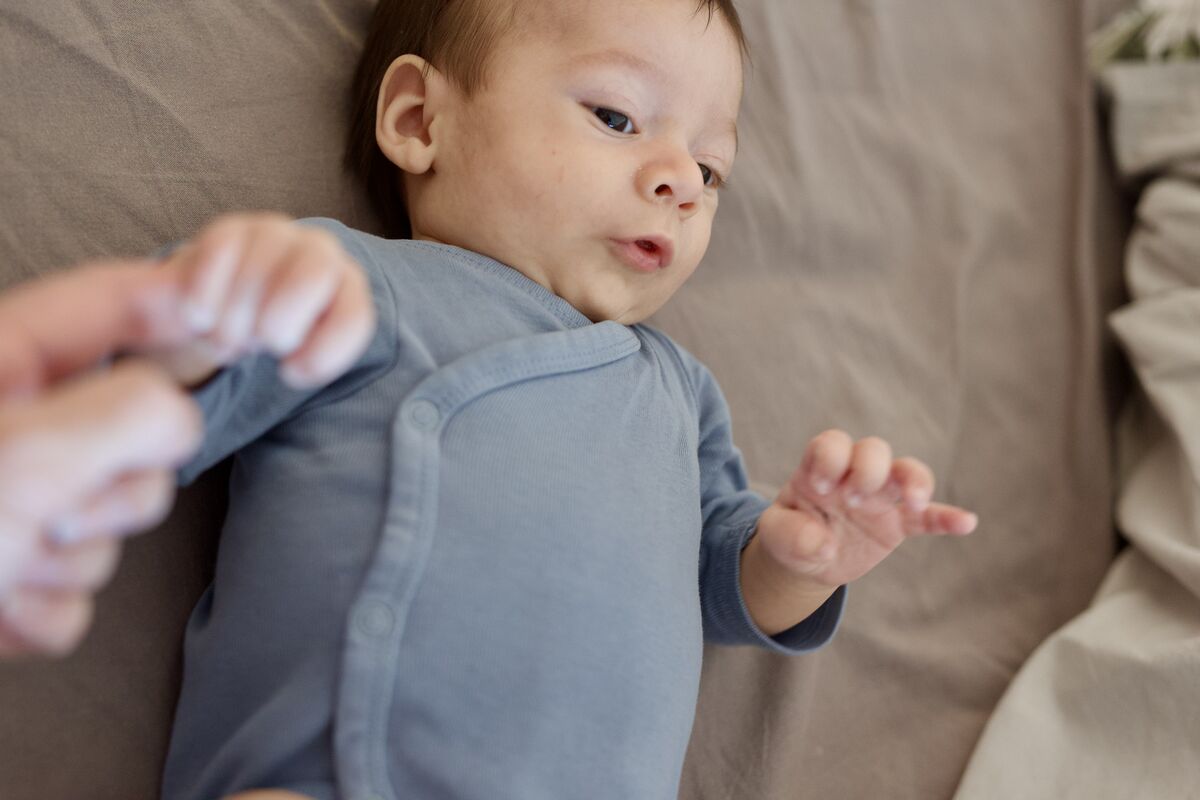 Baby reaching out while lying on the bed